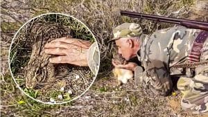 Un cazador acaricia y da un beso a una liebre encamada ante la mirada de sus perros