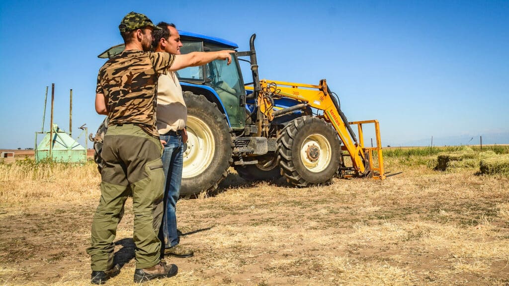Un agricultor y un cazador charlas junto al tractor.