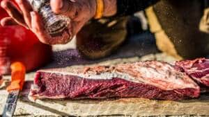 Un cazador echa pimienta sobre un trozo de carne de caza recién cobrada.
