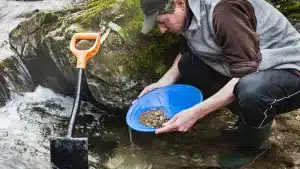 Un hombre busca oro en un río con su batea