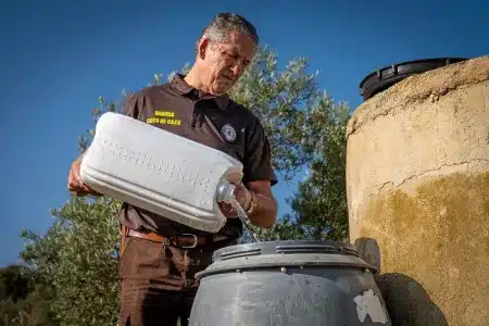 Un guarda de coto de caza rellena un bebedero.