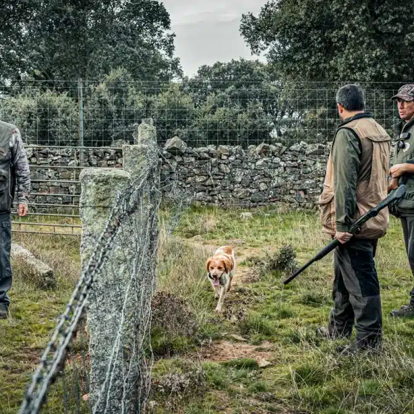 Unos cazadores ante la valla que delimita un acotado.