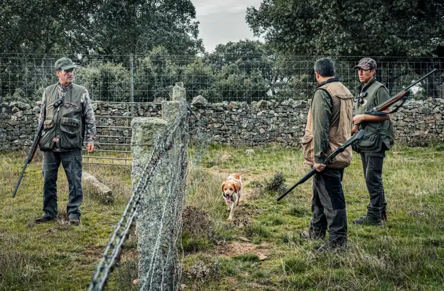 Unos cazadores ante la valla que delimita un acotado.