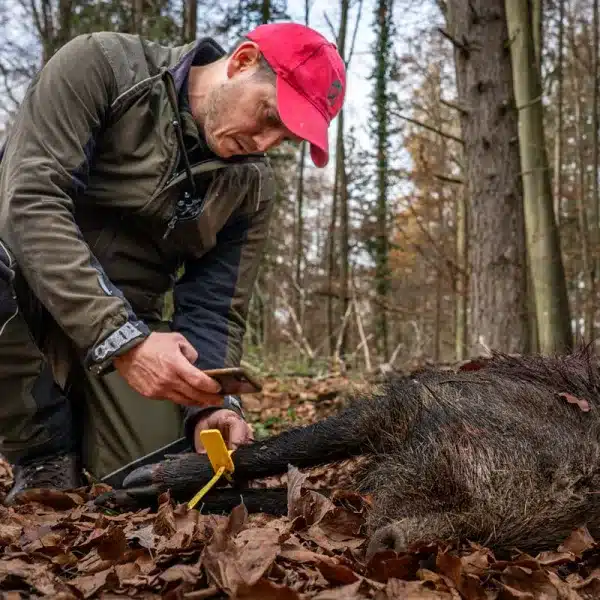 Un cazador junto a un jabalí.