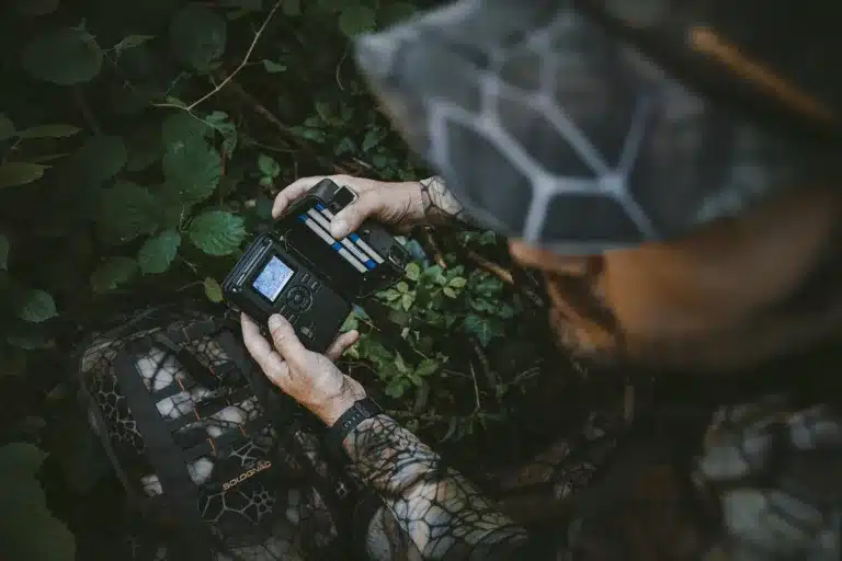 Un cazador revisando una cámara de fototrampeo